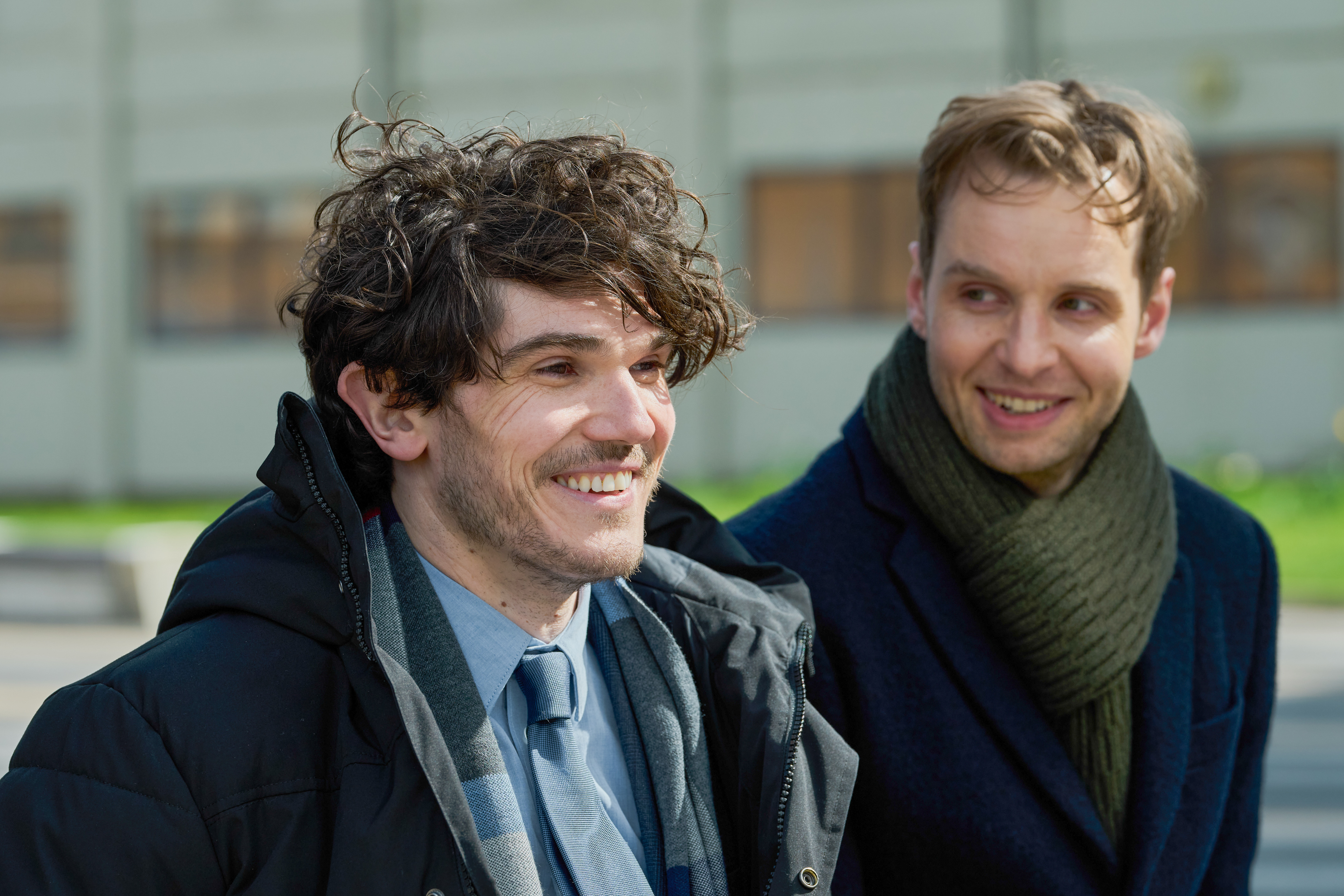 Two men share a smile while sitting outside